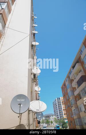 Satellitenschüsseln auf dem alten Haus. Satelliten-TV an der Wand eines mehrstöckigen Gebäudes. Satellitenschüssel Antennen . Ein Vogel sitzt mit an der Satellitenschüssel Stockfoto