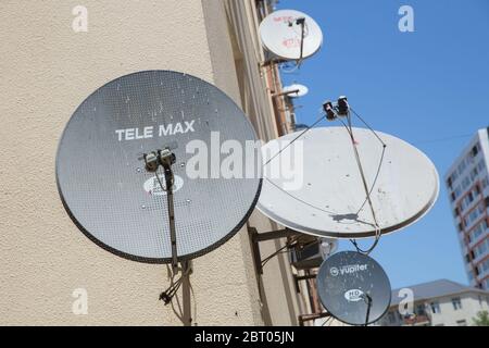 Satellitenschüsseln auf dem alten Haus. Satelliten-TV an der Wand eines mehrstöckigen Gebäudes. Satellitenschüssel Antennen . Ein Vogel sitzt mit an der Satellitenschüssel Stockfoto