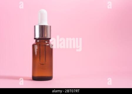 Eine Glasflasche mit Pipette mit weißer Gummispitze auf dem rosa Hintergrund. Naturhaut Konzept. Bio-Spa-Kosmetik. Nahaufnahme. Stockfoto