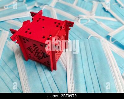 Roter Miniatur-Pavillon, der China auf einem Hintergrund von blauen Einweg-OP-Masken darstellt Stockfoto