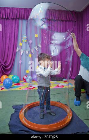 Seifenblasen zeigen. Kinderparty. Geburtstag der Kinder. Mit Seifenblase auf der Geburtstagsparty der Kinder spielen. Im Inneren der Seifenblase am Geburtstag Stockfoto