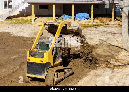 Mini Planierraupe Landschaftsbau arbeitet auf Bau mit Erde arbeiten, während Schaufelbagger Stockfoto