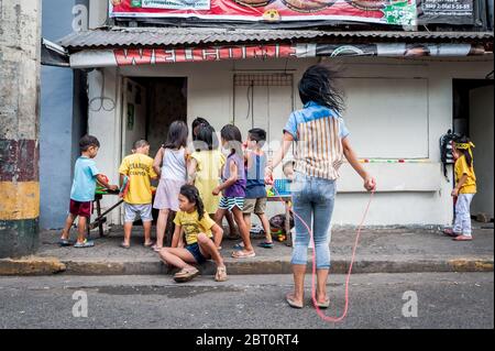 Junge philippinische Kinder spielen auf der Straße in der alten ummauerten Stadt Intramuros, Manila, Philippinen. Stockfoto