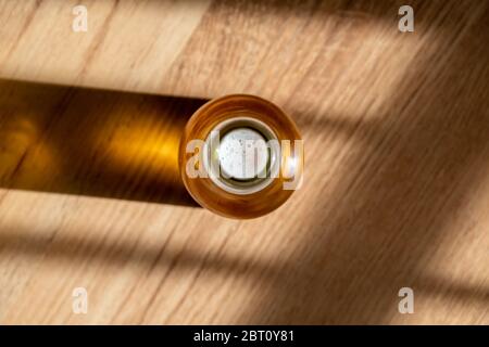 Ein Blick von oben auf eine kalte Flasche Bier an einem warmen Tag mit einem hölzernen Hintergrund. Stockfoto
