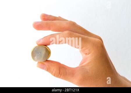 Eine länglich aufgeschnittene Obstbeere, die in der Hand einer jungen Frau gehalten wird, isoliert auf Weiß. Stockfoto