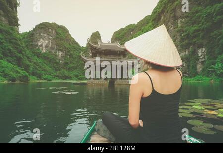 Asiatische Frau sitzt auf Holzboot während ihres Urlaubs in Ninh Binh Provinz, Vietnam Stockfoto