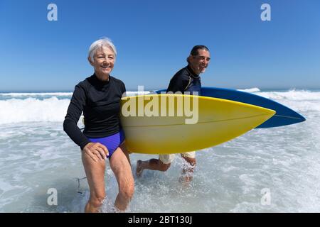 Ältere kaukasische Paar hält Surfbretter am Strand. Stockfoto