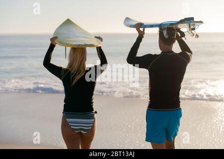 Kaukasisches Paar hält Surfbretter am Strand. Stockfoto