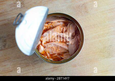 Nahaufnahme von offenem Thunfisch in roter Öl auf Holztisch, Draufsicht Stockfoto