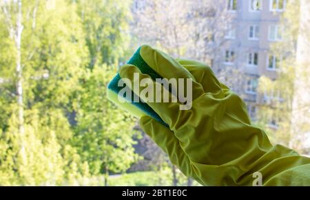 Eine Frau Hand in gelben Handschuhen wäscht das Fenster. Frühjahrsputz, Hausarbeit Konzept. Stockfoto