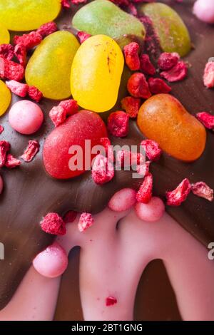 Gefriergetrocknete Himbeeren und Gelee-Bohnen Dekorationen auf dem fruchtigen Osterei der M&S-Ostersonntage Stockfoto