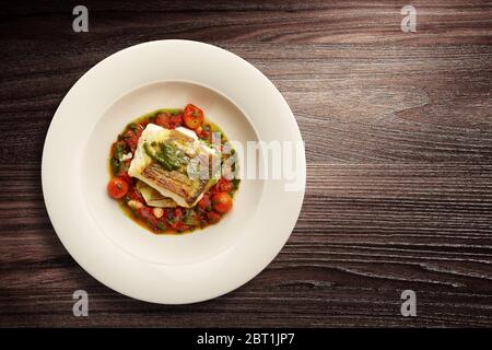 Direkt über dem Bild eines stilvollen Nouvelle Cuisine Tellers mit Fisch auf Gemüse auf Holzhintergrund Stockfoto