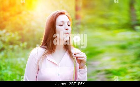 Mädchen im Wald bläst auf einen Löwenzahn Stockfoto