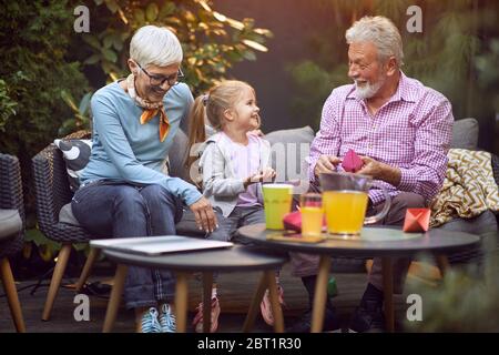 Fröhliches Mädchen, das gute Zeit mit ihren glücklichen Großeltern verbringt. Stockfoto