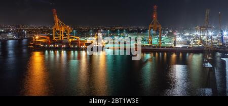 Nachtaufnahme. Lange Belichtung. Bridgetown Hafen mit Ladekranen und Frachtschiffen, die mit Containern beladen werden. Wunderschöne Lichter. Stockfoto