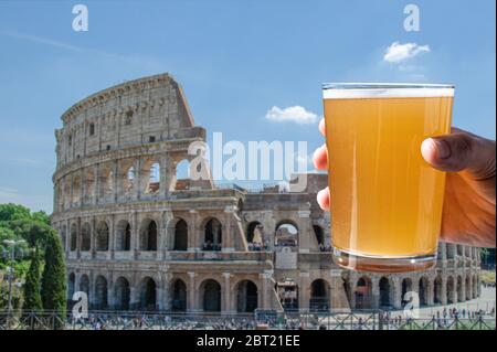 Mann hält ein Glas helles Bier auf dem Kolosseum (Kolosseum) Hintergrund in Rom, Italien Stockfoto