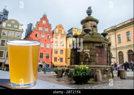 Ein Glas Bier vor dem Blick auf das Stadtzentrum von Stockholm auf Gamla Stan, Schweden. Stortorget in der Altstadt, dem ältesten Platz in Stockholm Stockfoto