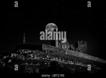 Der runde Turm auf dem Felsen von Cashel steht am Mond und ragt über die alte Klosterfestung aus dem 4. Bis 12. Jahrhundert Stockfoto