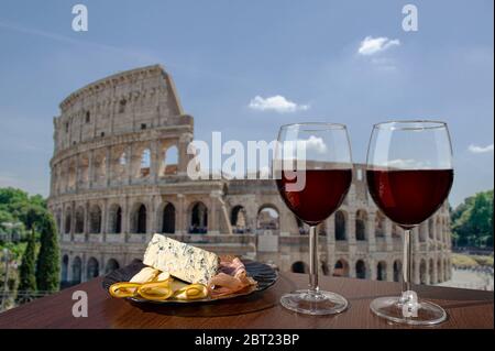 Zwei Gläser Wein mit Wurstwaren-Sortiment auf Sicht des Kolosseums in Rom, Italien. Ein Glas Rotwein mit verschiedenen Snacks - Käseplatte Stockfoto