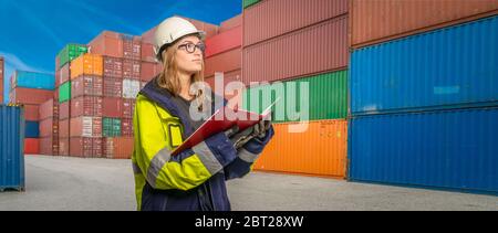 Eine Arbeitnehmerin in Schutzkleidung in einem Containerumschlagbereich Stockfoto