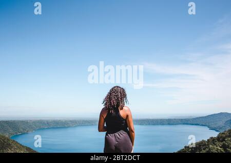 Mixed Race Millennial Backpacker Girl blickt vom Luftaussicht auf Laguna de Apoyo, einen Kratersee in der Nähe von Masaya, Nicaragua Stockfoto