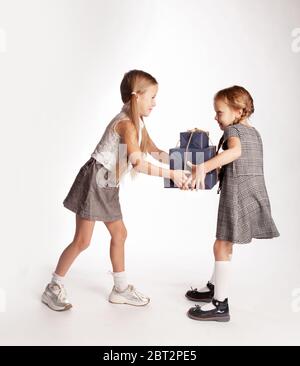 Zwei Mädchen kämpfen um Schachteln mit Geschenken. Jeder versucht, Geschenke in seine eigene Richtung zu ziehen. Stockfoto