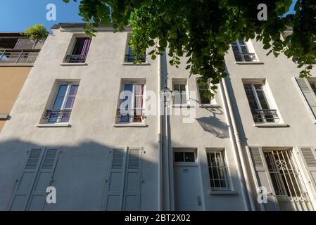 Niedrige Winkelansicht einer hellbeige Fassade mit Außenlaterne, die ihren eigenen Schatten wirft, Butte-aux-Cailles, Paris, Frankreich Stockfoto