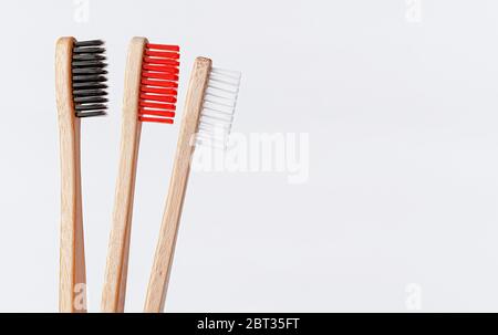 Rote, weiße und schwarze Bambuszahnbürsten auf weißem Hintergrund. Kopierbereich, Nahaufnahme. Stockfoto