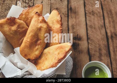 VENEZOLANISCHE KOLUMBIANISCHE KÜCHE. Venezolanische Typicals Mais Empanadas mit Fleisch in Tonschüssel mit Avocado-Sauce, gebratene Empanadas, gefüllt mit Huhn und Mea Stockfoto