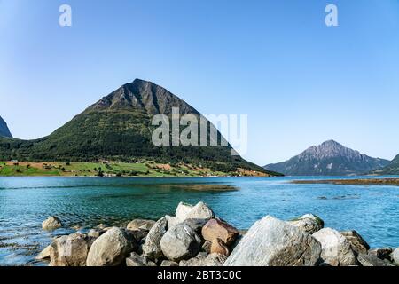 Panoramablick von Luroy bei ford mit Aldra Island (links), Olvika (Mitte) und einigen unbekannten hohen Bergen (links). Die Wand aus schweren Steinen auf sandigem B. Stockfoto