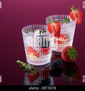 Strukturierte Gläser mit Gin Tonic und frischen Beeren auf schwarzem reflektierendem Hintergrund Stockfoto