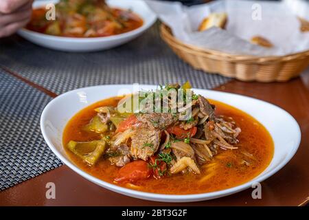 Gericht mit traditionellem asiatischen Nudel-Lagman mit Fleisch und Gemüse auf Holztisch. Stockfoto