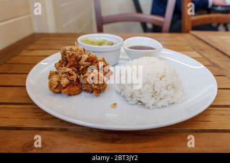 Im japanischen Restaurant werden auf einem Holztisch heimelige Gerichte wie Karaage oder japanisches gebratenes Huhn serviert, mit Misosuppe, Salat und gedünstetem Reis. Stockfoto