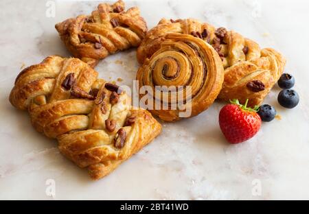 Auswahl an französischem, dänischem Gebäck mit Sommerfrüchten auf weißem Marmorgrund. Frühstück, Morgengenuss, kontinentales Café Stockfoto