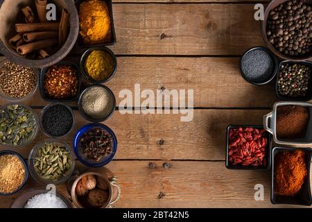 Schalen von Gewürzen übereinander auf einem Holztisch Stockfoto