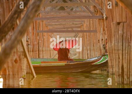 Novize Mönch in einem Boot unter U Bein Brücke bei Sonnenaufgang, Mandalay, Myanmar Stockfoto