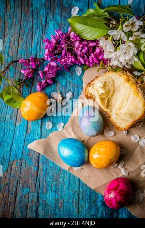 Bunte Ostereier, Blumen und Kuchen auf einem Holztisch Stockfoto