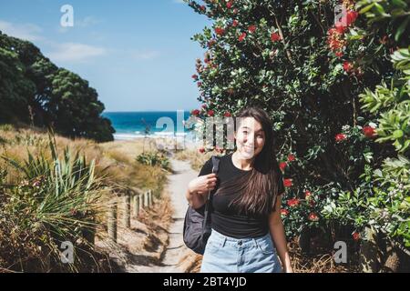 Lächelnde Frau auf dem Fußweg zum Strand, Mangawhai Heads, Northland, North Island, Neuseeland Stockfoto