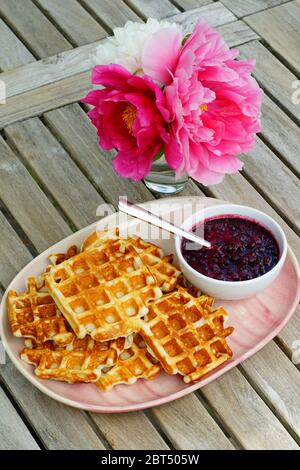 Teller mit frisch gebackenen Waffeln und frischem Beerenkompott zum Frühstück Stockfoto