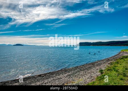 Lake Taupo auf einem hellen, sonnigen Tag unter einem blauen Himmel mit Wolken Stockfoto