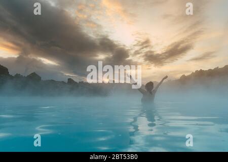 Frau in der Blauen Lagune mit den Armen in der Luft, Island Stockfoto