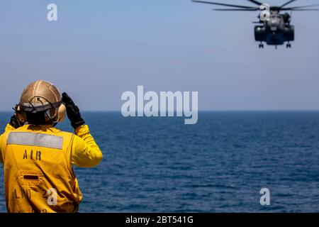 200504-N-GR168-1023 ARABIAN GULF (04. Mai 2020) Aviation Boatswain’s Mate (Handling) Airman Adrian Lopez, zugewiesen an das amphibische Transportdock Schiff USS New York (LPD 21), Signale an einen MH-53E Sea Dragon Hubschrauber, angebracht an der Blackhawks of Helicopter Mine Gegenmaßnahmen Squadron (HM) 15, auf dem Flugdeck von New York, 04.Mai 2020. New York, mit der Bataan Amphibian Ready Group und mit eingeschifften 26. Marine Expeditionary Unit, wird in den US 5. Flottenbereich der Operationen zur Unterstützung der Marineoperationen eingesetzt, um die maritime Stabilität und Sicherheit in der Zentralregion zu gewährleisten, Verbindung Stockfoto