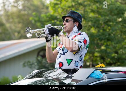 Austin, Texas, USA. Mai 2020. Ein Mann spielt 'Pomp and Circumstance No. 1', die traditionelle amerikanische Abschlussprozessionsmusik, auf Trompete, während die Oberstufe der Nachbarschaft in einer Auto-Parade reiten, um ihre Graduierung im Zuge der COVID-19 Pandemie zu feiern, die das Schuljahr verkürzte und die Absage traditioneller persönlicher Festlichkeiten erzwang. Etwa 30 Absolventen nahmen daran Teil, ohne zu wissen, ob College-Verpflichtungen im Herbst fortgesetzt werden. Kredit: Bob Daemmrich/Alamy Live News Stockfoto