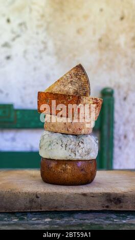 Verschiedene Käsesorten. Verschiedene Käseturm auf einem Holzbrett in rustikaler Umgebung. Stockfoto