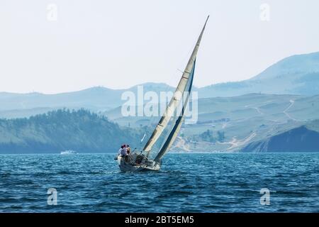 Yacht-Regatta mit einem Farbsegel in einem nebligen Morgenwagen auf dem Meer. Breites Panorama. Stockfoto