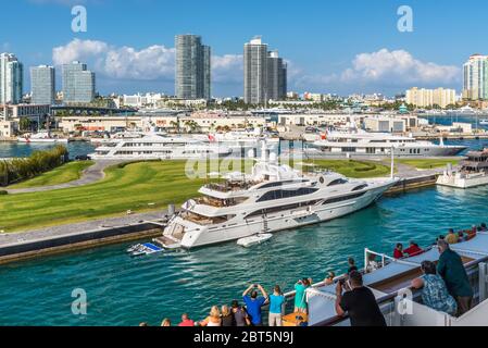 Miami, FL, USA - 28. April 2019: Passagiere auf dem Deck eines Kreuzfahrtschiffes genießen den Blick auf Miami, Florida, USA und Luxusyacht Stockfoto