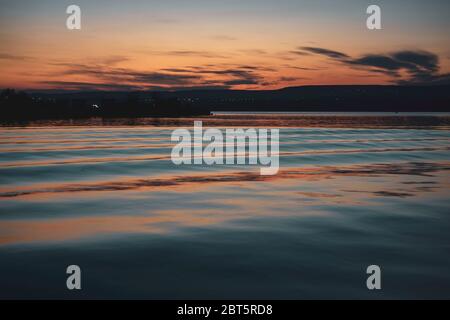 Milde Wellen in einem See während des Sonnenuntergangs mit filmischen Farbgraden Stockfoto