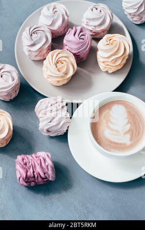 Heißer Kaffee mit Latte Art und rosa Marsmalow auf grauem Hintergrund St. Valentinstag Konzept. Draufsicht Stockfoto