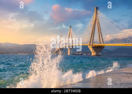 Moderne Brücke am Abend Sonnenuntergang Zeit mit Wellen spritzen. Rion-Antirion-Brücke, Griechenland, Europa. Die Rion-Antirion-Brücke in Griechenland eine der Welt' Stockfoto