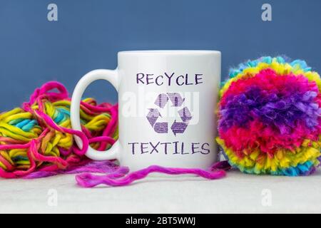 Selbstgemachtes Pom Pom aus recycelter Wolle, mit Becher. Recyceln Sie Textilien Text und Symbol auf Tasse. Nachhaltiges Wohnen zu Hause Konzept Stockfoto